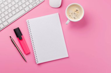 Ofis malzemeleri, kahve fincanı ve boş not defteri olan pembe bir masa. Kopyalama alanı olan kadınsı ve yaratıcı çalışma alanı