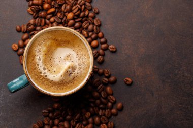 Zengin, aromatik kavrulmuş kahve çekirdekleri ile çevrili buharda pişmiş bir fincan taze kahve. Sıcaklığın, enerjinin ve kafeine olan sevginin mükemmel bir temsili.