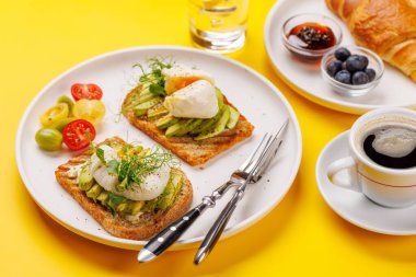 Lezzetli avokado tostlarıyla kahvaltı mükemmel pişmiş yumurta ve böğürtlenli gevrek kruvasan ve reçelli