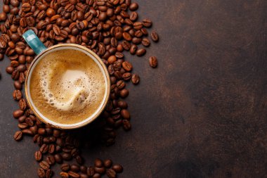 Zengin, aromatik kavrulmuş kahve çekirdekleri ile çevrili buharda pişmiş bir fincan taze kahve. Sıcaklığın, enerjinin ve kafeine olan sevginin mükemmel bir temsili.