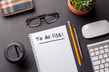 Bilgisayarlı düzenli çalışma masası, ofis malzemeleri, kahve ve yapılacaklar listesi için bir not defteri. Temiz, üretken planlı üst görünüm