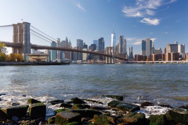 Manhattan 'ın ufuk çizgisine uzanan ikonik Brooklyn Köprüsü' nün çarpıcı panoramik görüntüsü, berrak gökyüzü altında zamansız mimari güzelliğini ve şehir cazibesini yakalıyor.