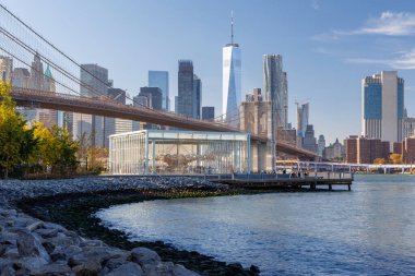 Manhattan 'ın ufuk çizgisine uzanan ikonik Brooklyn Köprüsü' nün çarpıcı panoramik görüntüsü, berrak gökyüzü altında zamansız mimari güzelliğini ve şehir cazibesini yakalıyor.