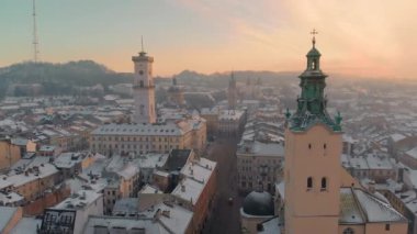 Aerial drone view of Lviv cityscape in winter, Western Ukraine. Lviv old town covered with snow. Central market square with a City Hall, old churches and historic buildings in winter at sunset