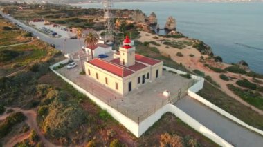 Portekiz 'in Algarve bölgesindeki Lagos kasabasında günbatımında uçurumun kenarındaki Ponta da Piedade deniz fenerinin hava manzarası. Farol da Ponta da Piedade Lagos 'un insansız hava aracı görüntüleri. Yörünge atışı