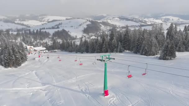 スキー場とスキーチェアリフトのある冬の山の風景日没 空の山スキー場の空中ドローンビュー 雪はスプルースの森と雪の間のリフトをカバーしました 軌道ショット — ストック動画