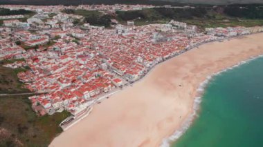 Portekiz kıyı kasabası Nazare, Portekiz. Nazare kasabasındaki uzun kumsal boyunca tarihi binalar, sahil beldesi, Portekiz. Hava aracı görüntüleri. Yörünge atışı