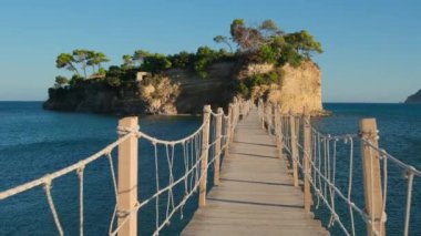 POV, Yunanistan 'ın Zakynthos adasındaki Agios Sostis yakınlarındaki küçük Cameo adasına giden tahta köprü üzerinde yürüyor. Gün batımında Zante 'deki popüler turistik yere tahta köprü. Sabit görüntü. 