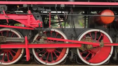 Buharlı tren lokomotifi yaklaşıyor. Eski tarz trenin tekerleklerinin izini sürüyorum. Eski demir demiryolu lokomotifi tekerlekleri yakın plan. Tarihi ulaşım teknolojisi konsepti. Retro tren ağır çekimde