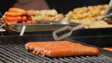 Avrupa 'daki geleneksel Noel festivalinde ızgara sosis. Marketteki ızgaranın üzerindeki sosisleri yakın plan çek. Şef kışın yemek festivalinde yüksek sıcakta et sosisi pişiriyor.