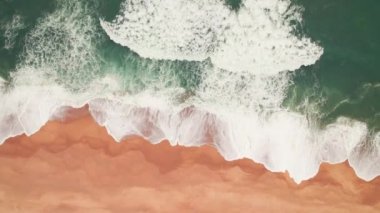Portekiz 'de fırtınalı Atlantik okyanus dalgaları olan boş bir plajın hava görüntüleri. Kuşlar kumsaldaki büyük dalgaların ve karanlık okyanus suyunun drone görüntülerini görüyorlar. Okyanus kıyısının yukarıdan görünüşü