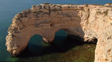 Portekiz, Marinha sahilindeki doğal kemerin hava görüntüsü. Güney Portekiz 'in Algarve bölgesinde turkuaz deniz suyuyla Marinha sahilindeki kayalık kemerleri.