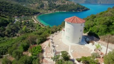 Yunanistan 'ın geleneksel yel değirmeni ve güzel Paralia Dexia koyunun Ithaca Adası, Kefalonia, İyon Denizi, Yunanistan' daki turkuaz deniz suyuyla hava manzarası. Uçan ileri taşıyıcı. Ithaki adası manzarası 