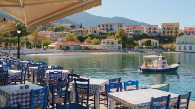 Idyllic view of the picturesque fishing village of Assos, Kefalonia island, Greece. Small fishing boat moored near traditional outdoor Greek restaurant in beautiful Assos village. Still shot