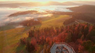 Tree top observation tower in resort town Krynica-Zdroj at sunrise, Lesser Poland Voivodeship. Aerial drone shot of the wooden loookout tower, Krynica. Fogy morning landscape in Beskid Mountains
