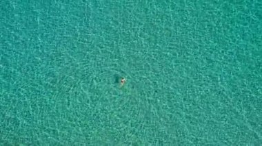 Aerial view of a woman swimming in crystal clear turquoise sea water. Top down view of a swimming woman in clear azure water. Transparent water in Ionian sea, Greece. 