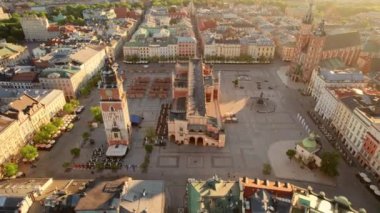 Main Market square or Rynek Glowny with a Town Hall, Sukiennice and St. Marys Basilica church at sunrise in Krakow, Poland. Aerial view of the Krakow central square in morning. Orbit shot