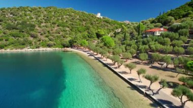 Flaying over the beautiful Paralia Dexia bay with turquoise sea water on Ithaca island, Kefalonia, Ionian sea, Greece. Ithaki island idyllic destination scene. Traditional Greek windmill on the hill 