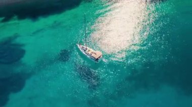 Yukarıdan bakıldığında, turkuaz kristal berrak suda yüzen beyaz bir yelkenlinin çarpıcı hava manzarası. Kefalonia, İyon denizi, Yunanistan. Drone yörünge atışı 