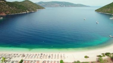 Yunanistan 'ın Kefalonia adasındaki Antisamos plajında kristal berraklığında masmavi bir su. Yunanistan 'ın İyon Adası' ndaki Kefalonia Adası 'nda güneşli yataklı cennet sahili manzarası. yörünge atışı