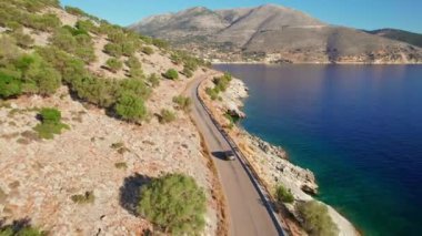 Aracın İyon Denizi, Yunanistan 'daki Kefalonia adasındaki güzel bir sahil yolunda sürüşünü gösteren hava aracı görüntüleri. Cephalonia 'daki güzel Akdeniz manzarası. Yunan bayramı konsepti sırasında kiralık araba