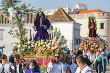 Tavira, Portekiz - 10 Nisan 2022: Portekiz 'in Algarve bölgesinde Paskalya öncesi Pazar günü Palm Sunday' de Zafer Yürüyüşü. Tavira üzerinden İsa 'nın heykelini taşıyan kimliği belirsiz insanlar.
