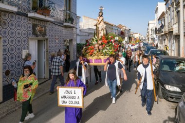 Tavira, Portekiz - 10 Nisan 2022: Portekiz 'in Algarve bölgesinde Paskalya öncesi Pazar günü Palm Sunday' de Zafer Yürüyüşü. Tavira üzerinden İsa 'nın heykelini taşıyan kimliği belirsiz insanlar.
