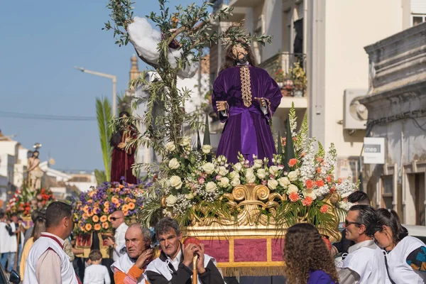 Tavira, Portekiz - 10 Nisan 2022: Portekiz 'in Algarve bölgesinde Paskalya öncesi Pazar günü Palm Sunday' de Zafer Yürüyüşü. Tavira üzerinden İsa 'nın heykelini taşıyan kimliği belirsiz insanlar.