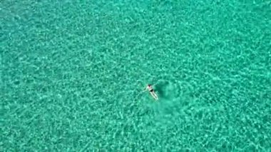 Aerial view of a woman swimming in crystal clear turquoise sea water. Top down view of a swimming woman in clear azure water. Transparent water in Ionian sea, Greece.