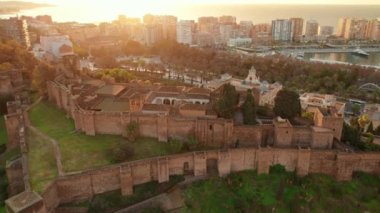 İspanya 'nın Endülüs bölgesindeki Malaga' da Ortaçağ Mağribi şatosunun gündoğumunda havadan görünüşü. Drone yörünge atışı. Tepedeki tarihi kale. Güzel bir sabah ışığında Malaga şehri.