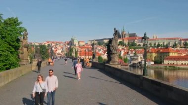 Prag, Çek Cumhuriyeti - 14 Haziran 2022: Prag 'da güneşli bir günde tarihi heykelleri olan Charles Köprüsü. İnsanlar en ünlü Karlov köprüsünde yürüyor. Arka planda Prag kalesi. Praha 'da yaz