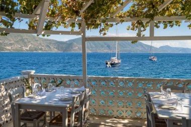 Kefalonia adasında güzel bir açık hava tavernası var. Deniz kıyısında samimi bir açık hava restoranı ve sakin denize demirlemiş lüks yatları olan İyon adalarından tipik bir Yunan manzarası. Yunanistan 'da Tatil.