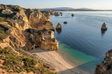 Praia do Camilo beach at sunrise near Lagos town, Algarve province, Portugal. White sand beach with in rocky lagoon.