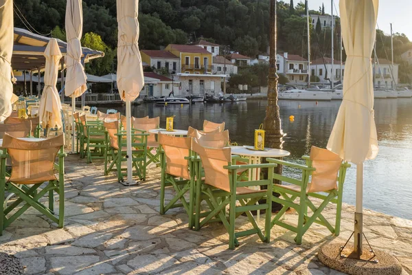 Cozy outdoor cafe on the waterfront of picturesque Kioni village in Ithaca island at sunrise, Kefalonia, Ionian sea, Greece. Early morning on a Greek island in summer