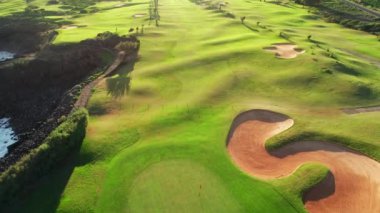 İspanya 'nın Kanarya Adaları' ndaki Tenerife Adası 'nda günbatımında bir golf sahasının havadan görünüşü. Tenerife adasının kayalık sahilindeki golf sahasında, gün batımının olduğu resim gibi bir manzara. Lüks varış sahnesi
