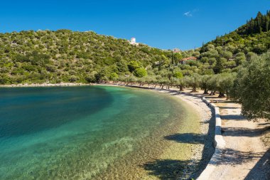 Ithaca Adası, Kefalonia, İyon Denizi, Yunanistan 'da turkuaz deniz suyuyla güzel Paralia Dexia Körfezi. Ithaki Adası cennet gibi bir yer. Tepedeki geleneksel Yunan yel değirmeni