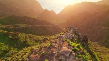 Masca Vadisi, Tenerife, Kanarya Adaları 'ndaki yeşil volkanik manzarada gün batımını izleyen bir kadın. Tenerife adasının hava manzarası. Seyahat yeri, Kanarya adaları manzarası