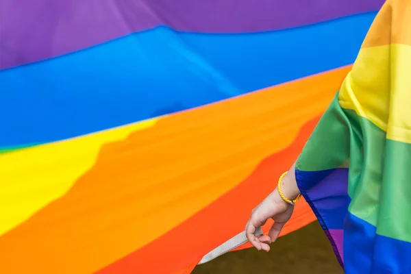 Stock image Unidentified woman holding big rainbow flag during LGBT pride. Pride community celebrating love and diversity carrying big flag during lesbian gay bisexual and transgender march.