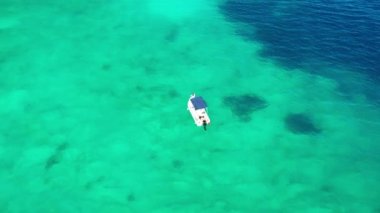 Turkuaz kristal şeffaf suda yüzen küçük bir motorlu teknenin hava görüntüleri. Kefalonia, İyon denizi, Yunanistan. Drone yörünge atışı. Turist sürat teknesi sahile yakın demirlemiş. Yukarıdan görüntüle