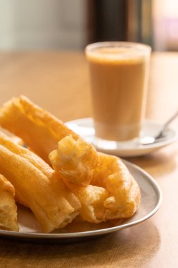 Arka planda sütlü bir bardak kahve ile taze pişmiş Churros. Popüler İspanyol tatlısı. Tenerife, Kanarya Adaları 'ndaki geleneksel churreria kafesinde taze Churros tabağı.