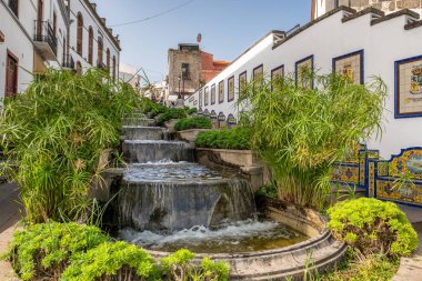 Famous Paseo de Canarias street in Firgas town, Gran Canaria, Canary Islands, Spain. Tasteful waterfall cascade on Paseo de Gran Canaria clipart