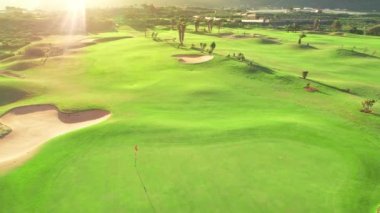 İspanya 'nın Kanarya Adaları' ndaki Tenerife Adası 'nda günbatımında bir golf sahasının havadan görünüşü. Tenerife adasının kayalık sahilindeki golf sahasında, gün batımının olduğu resim gibi bir manzara. Lüks varış sahnesi