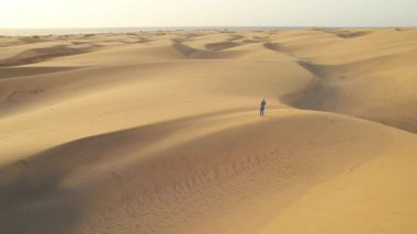 Güneş doğarken Playa del Ingles sahilindeki Maspalomas Kumulları, Maspalomalar, Gran Kanaryası, Kanarya Adaları, İspanya. Bir kadın, Büyük Kanarya 'nın görkemli çöl manzarasında yürüyor..