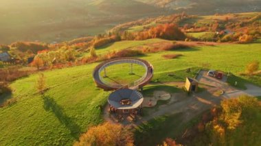 Polonya 'nın küçük Voyvoda bölgesinde, günbatımında sonbahar dağlarında bir salyangoz izleme platformunun güzel hava manzarası. Kırsal bölgelerdeki çarpıcı sonbahar renkleri. Tahta gözetleme kulesi.