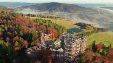 Güneş doğarken, tatil köyü Krynica-Zdroj 'daki ağaç tepesi gözlem kulesi, Küçük Polonya Voyvoda' sı. Tahta gözetleme kulesinin hava manzarası, Krynica. Beskid Dağları 'ndaki sisli sabah manzarası