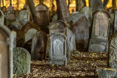 Gece eski bir mezarlıkta mezar taşları. Örtülü mezar taşları ürkütücü bir sahne yaratır. Eğik mezar taşları, karanlık bir sonbahar ortamında ürkütücü bir ortam yaratıyor. Mezarlıktaki ürkütücü yaşlı mezar taşları.