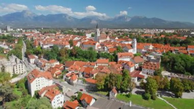 Slovenya 'nın arka planında dağ sırasına sahip Kranj kasabasının hava manzarası. Kranj, Slovenya 'nın üçüncü büyük kentidir. Drone yörünge atışı. Güneşli bir günde Kranj şehir manzarası. 