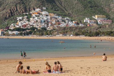 Tenerife, İspanya - 24 Ocak 2023: Tenerife, Kanarya Adaları 'ndaki San Andres tatil köyü yakınlarındaki güzel Las Teresitas plajında kimliği belirsiz gençler.