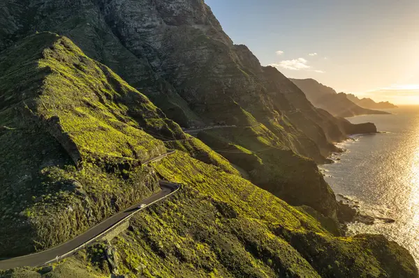 Coastline road at sunset on Gran Canaria Island, Canary Islands, Spain. Majestic volcanic mountains and Atlantic ocean landscape. Aerial view of Gran Canaria coast at sunset. Car trip in Spain