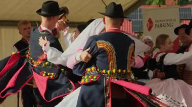 Malopolska, Polonya - 23 Temmuz 2023: Ulusal Polonyalı kostümlü insanlar yavaş çekimde geleneksel danslar yapıyorlar. Geleneksel folklor kostümleriyle yapılan halk dansının yakın plan çekimi.